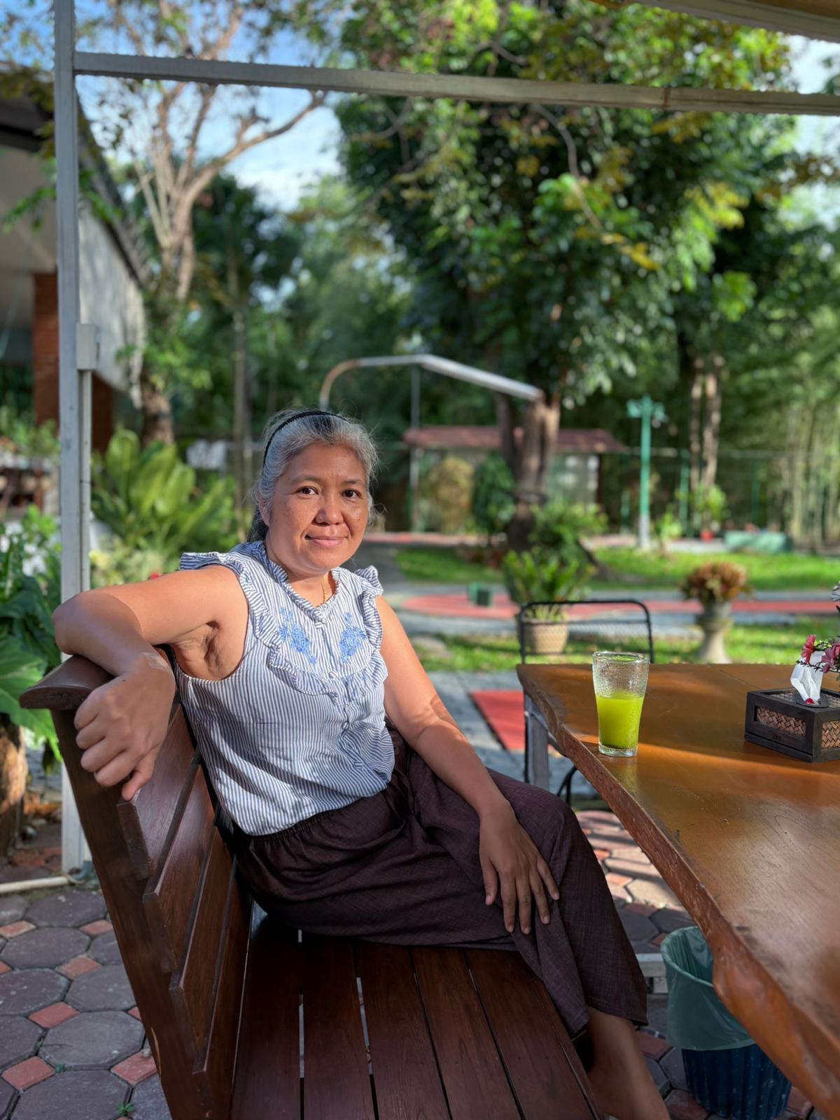 Dr. Sirichan seated in the garden at Green Oasis Resort, San Kamphaeng